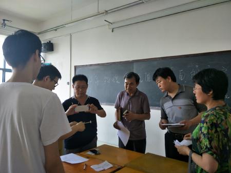 潘治钢和张春华、任天忠、石会萍三位评委老师观看自制低值教具大赛